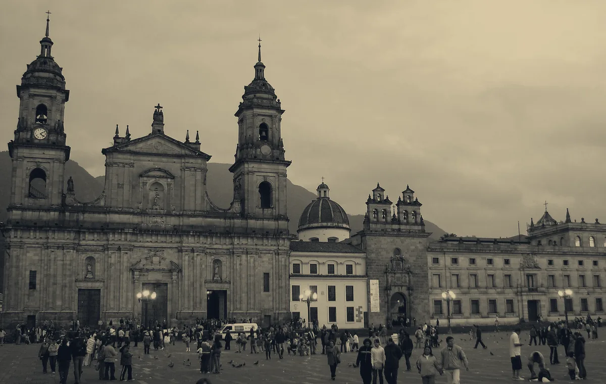 Catedral Primada y Plaza de Bolívar de Bogotá al atardecer, con personas en la plaza
